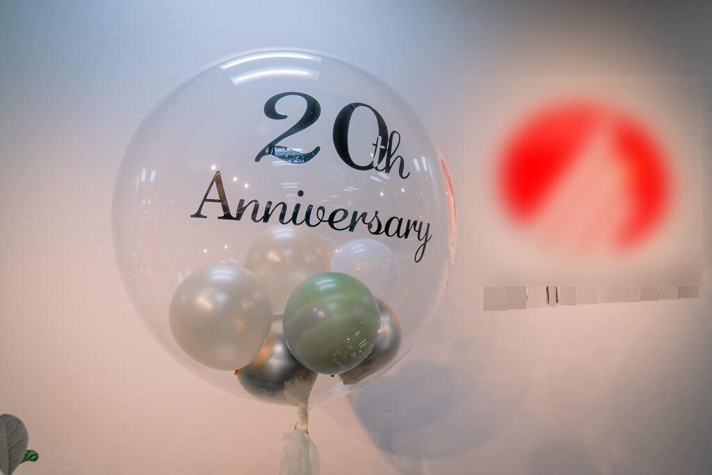 グリーンとシルバーで彩る20周年記念バルーンとスタンド花の飾り付け