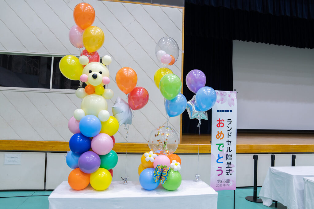 ランドセル贈呈式を彩るカラフルなバルーンのクマと虹色ガーランドの飾り付け