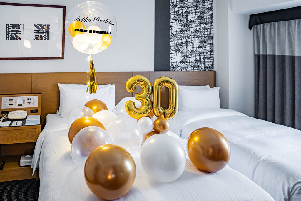 ホテル客室でのゴールドと白の「30」バルーン誕生日お祝い飾り付け