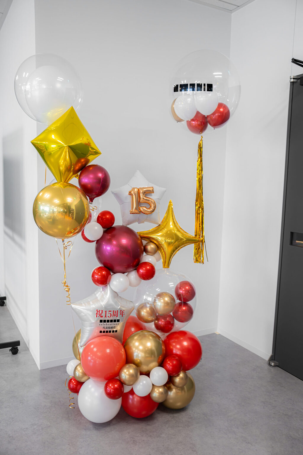 渋谷のオフィスを彩る赤とゴールドの15周年お祝いバルーンスタンド飾り付け