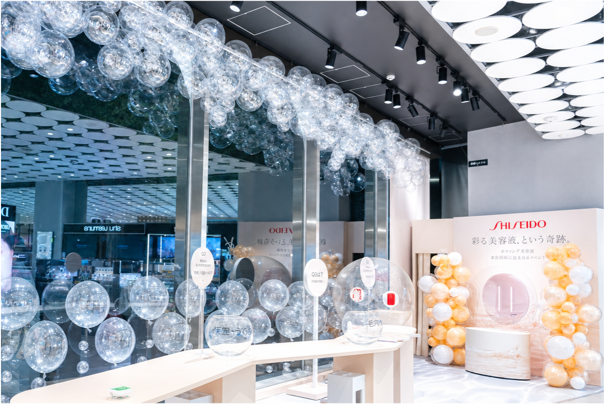 天井から吊るしたクリアバブルバルーンのガーランドとオレンジ・ホワイトのバルーンタワーによるコスメブランド店頭装飾